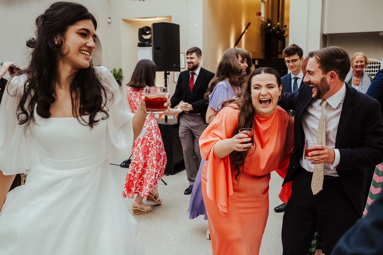 Wedding celebration with guests dancing and laughing in formal attire.