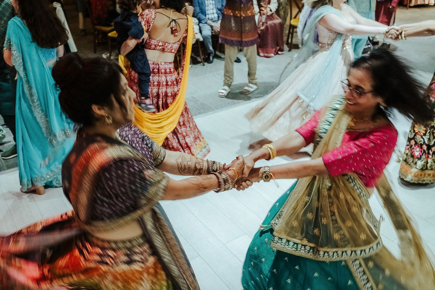 Women in colorful traditional Indian dresses dance together during celebration.