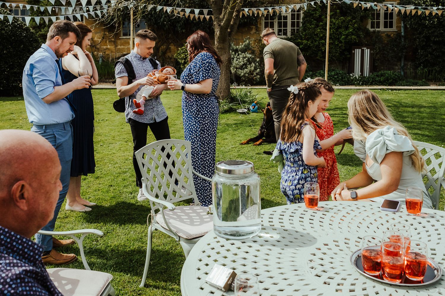 Summer garden party with guests mingling around decorated table with red drinks.
