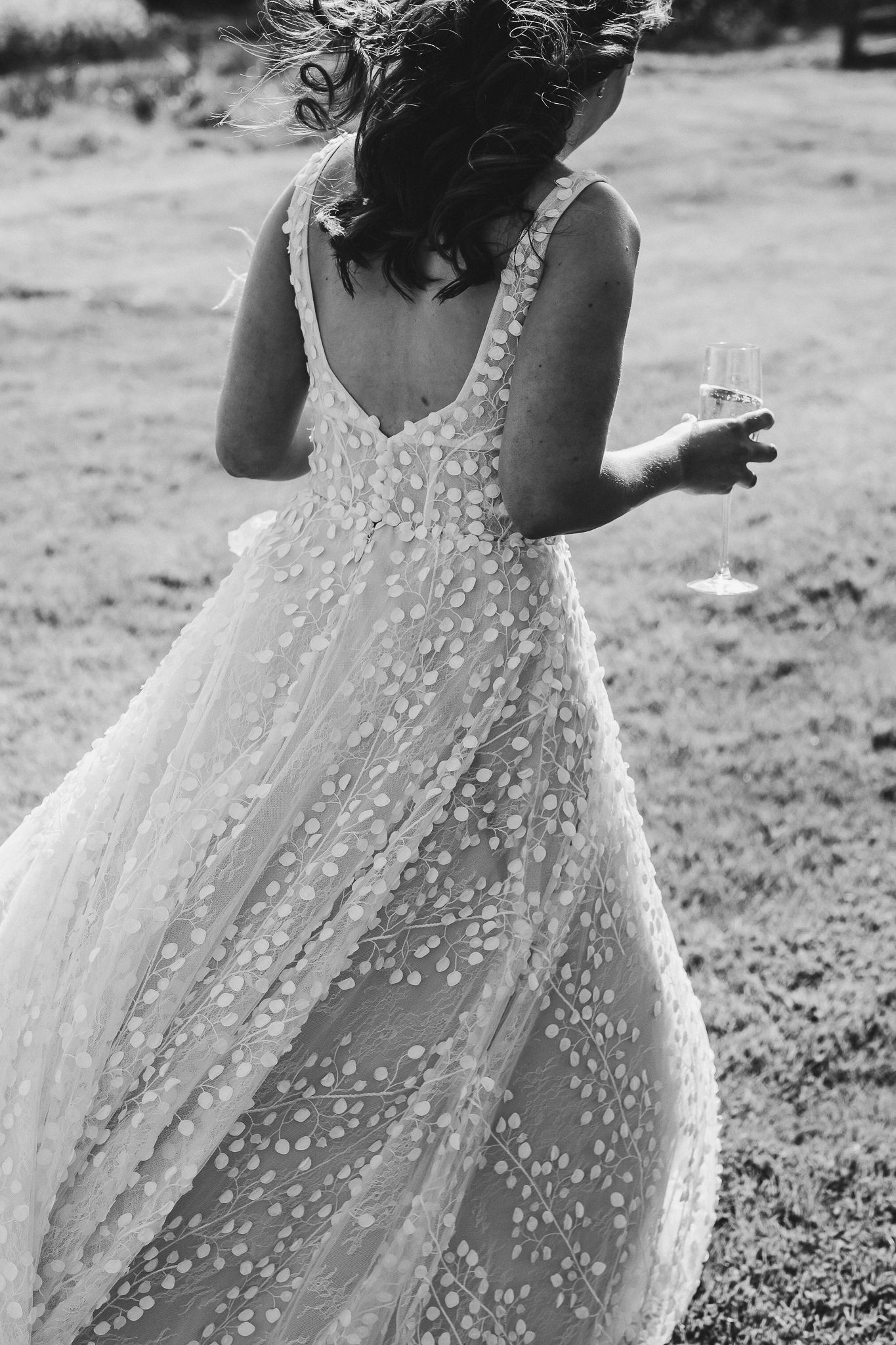Back view of a flowing wedding dress with delicate floral details in black and white.