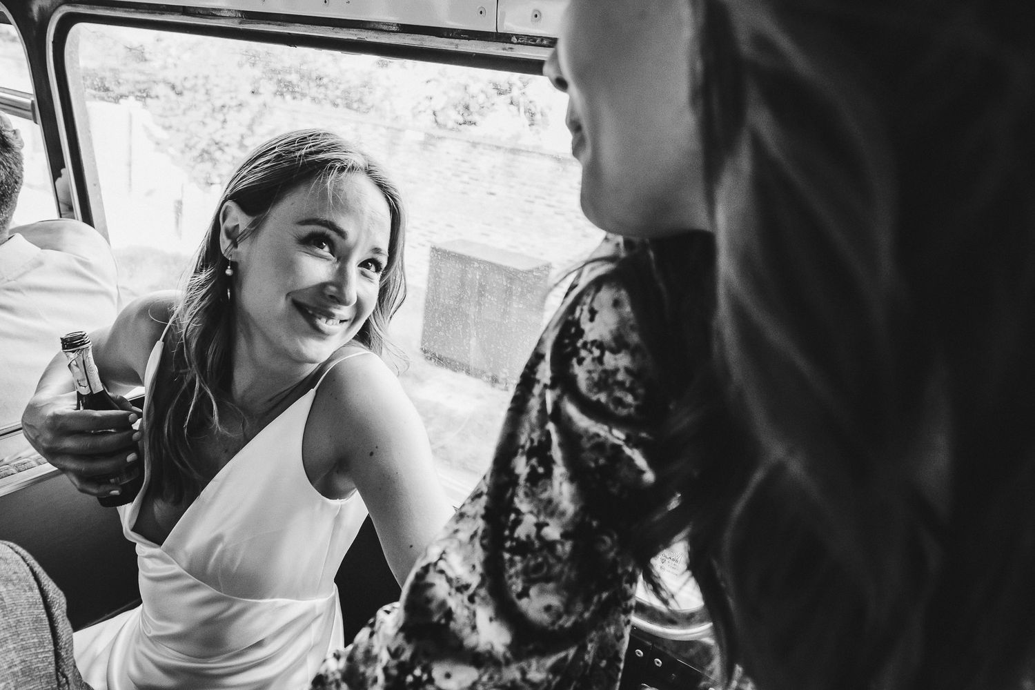 Candid moment captured of wedding guests enjoying a ride in a vintage bus.