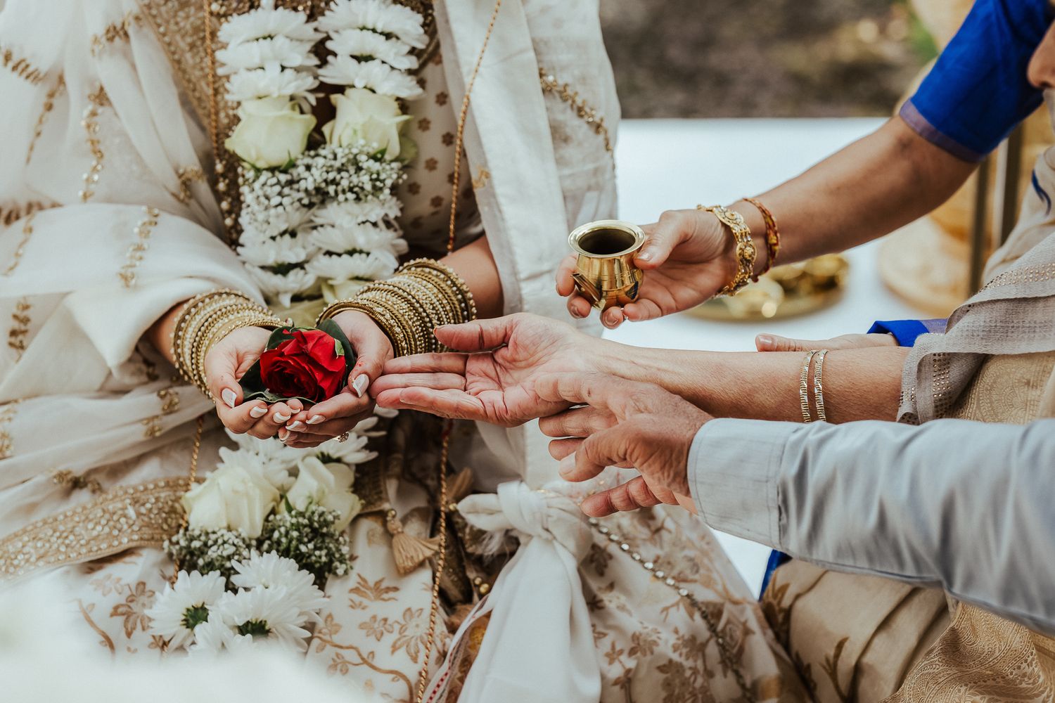 Traditional henna adorned hands accept a cup of coffee during a cultural ceremony in ornate wedding attire.