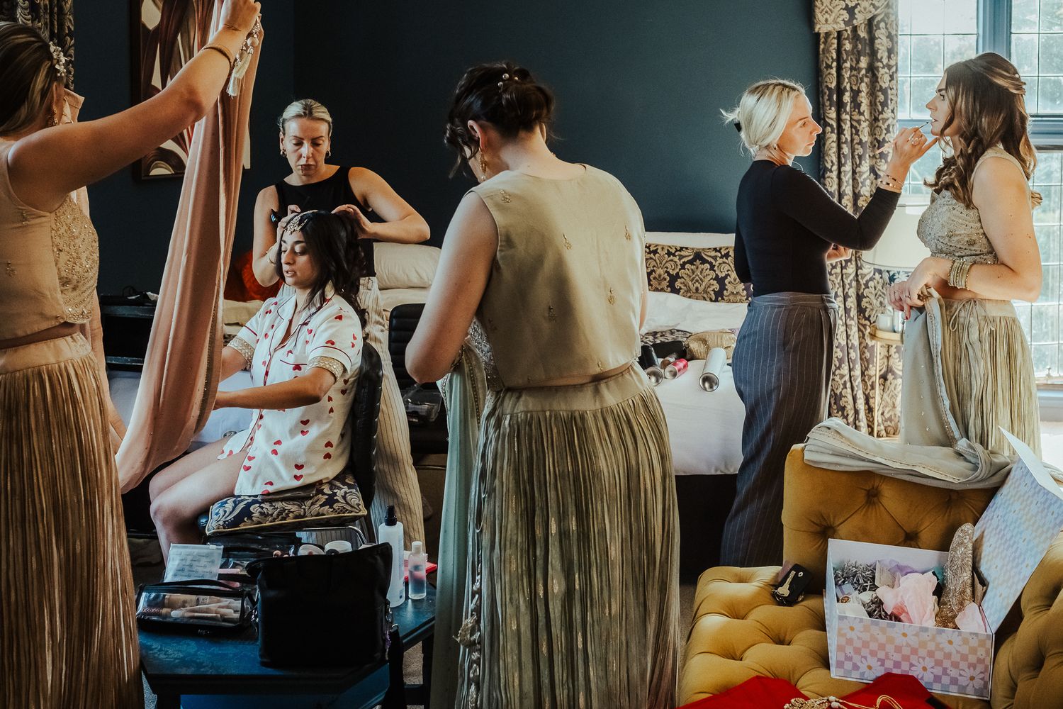 Behind the scenes view of a wedding party getting ready in a dressing room with stylists and bridesmaids.