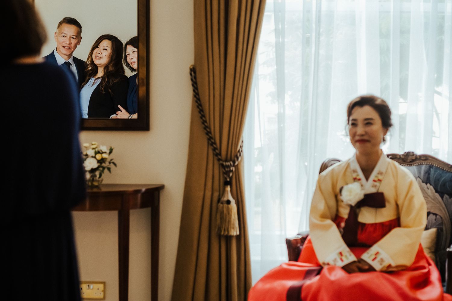Wedding party attendees share joyful moments in an elegant room with golden curtains.