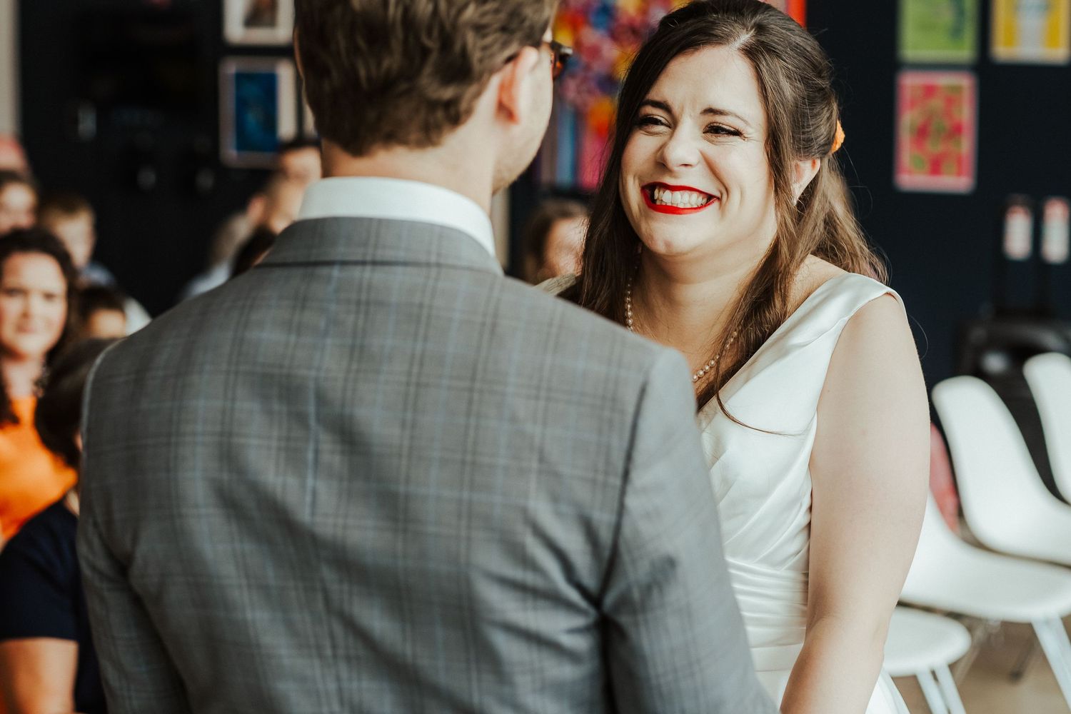 Couple shares joyful moment during wedding ceremony in modern venue with art-covered walls.