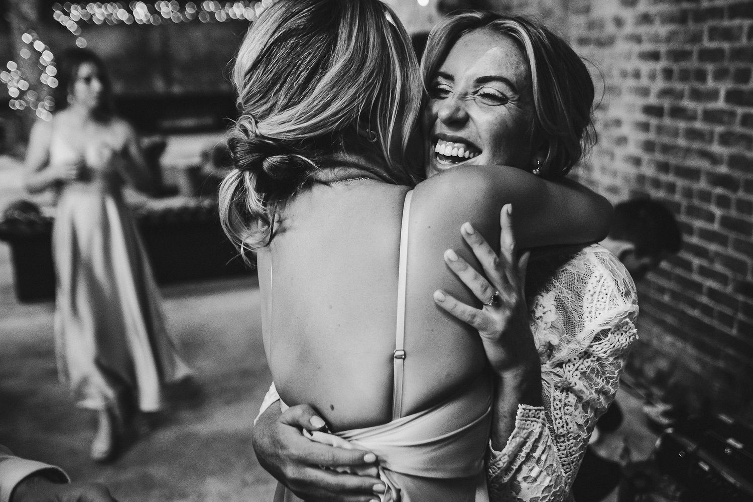 Black and white photo shows joyful embrace during wedding celebration.