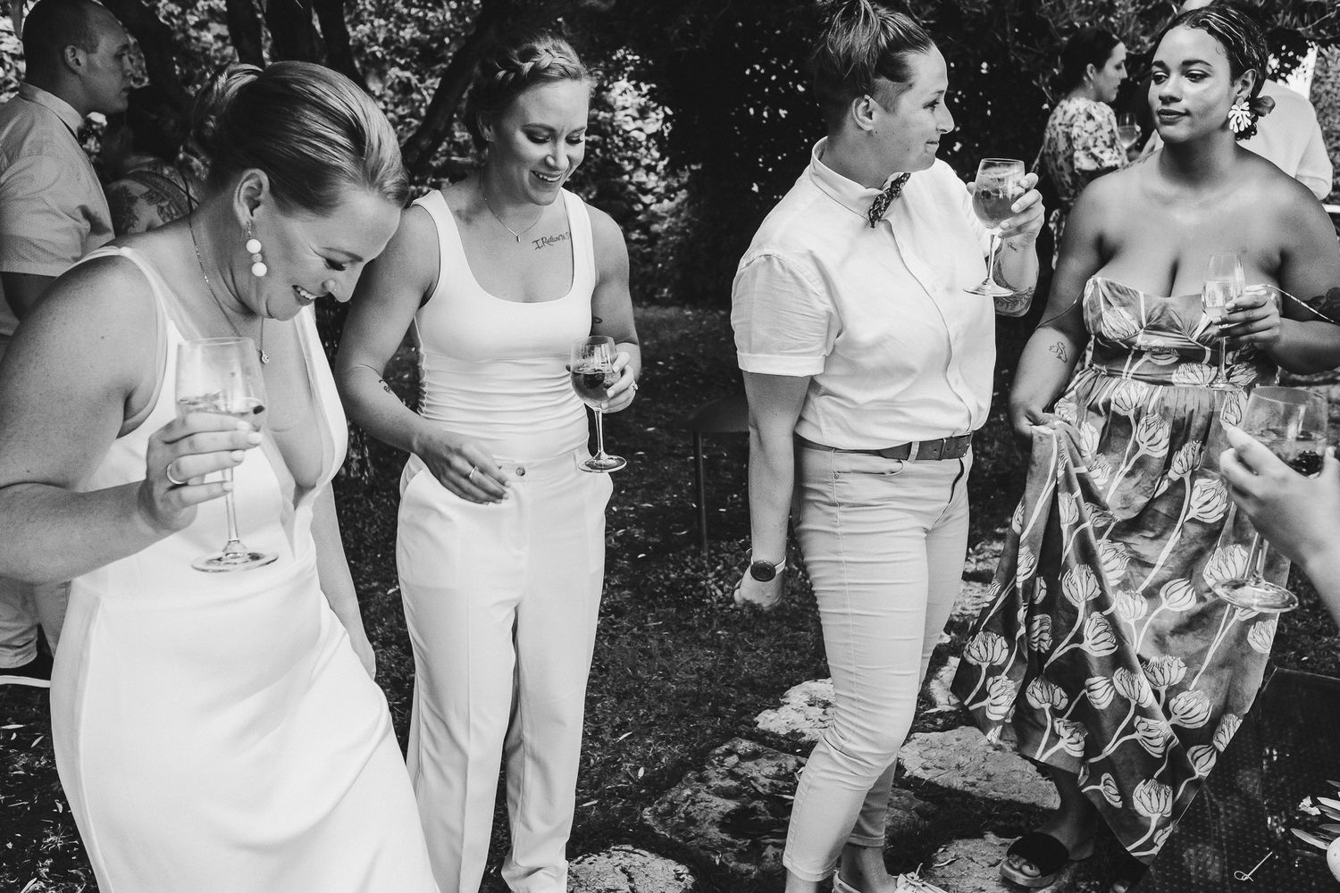 Wedding guests in summer attire socializing during an outdoor garden reception.