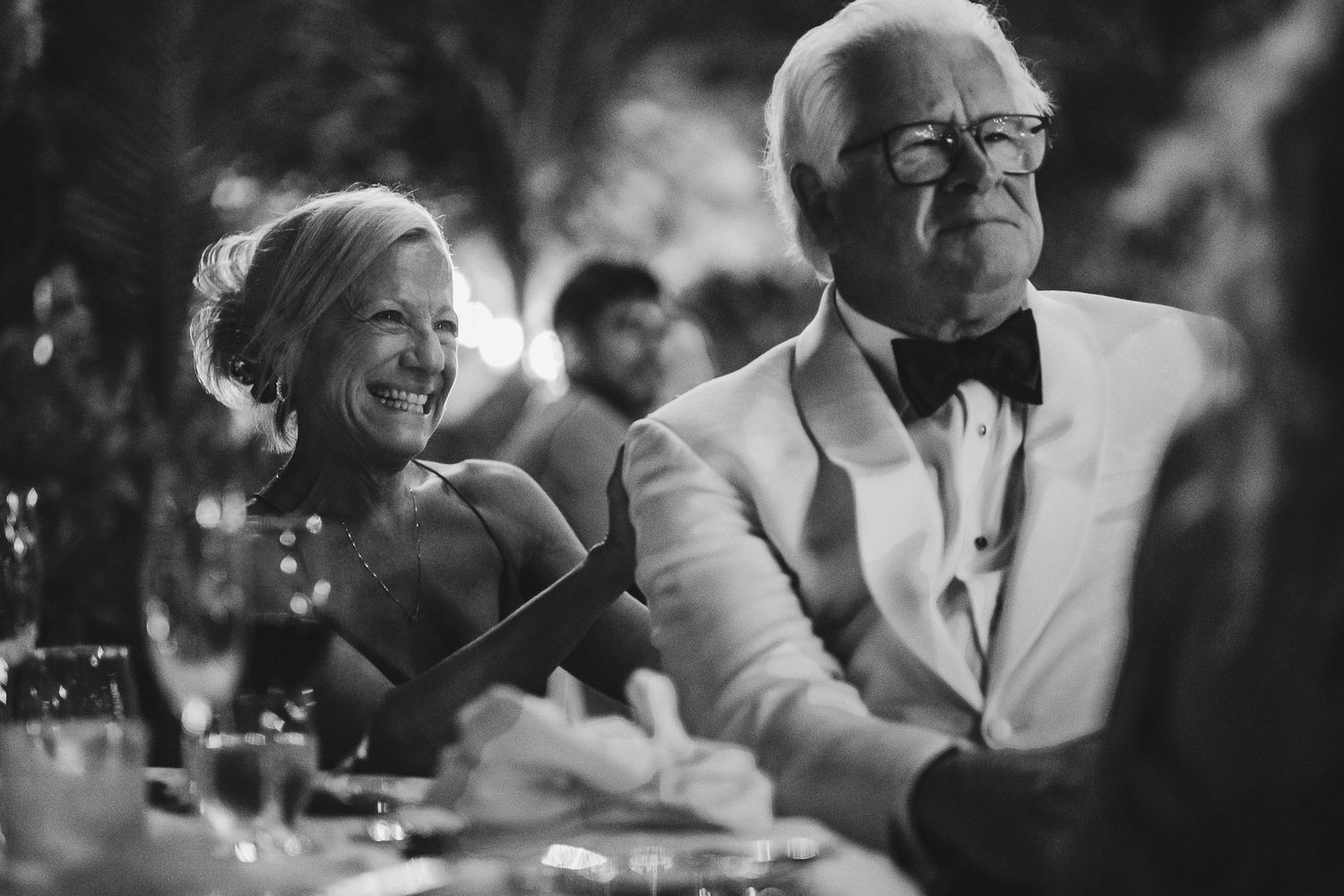 Black and white photo of guests sharing a heartfelt moment during wedding reception.