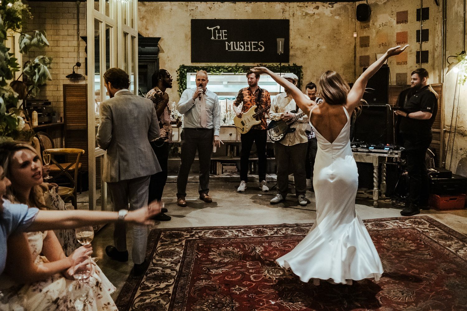 Bride dances joyfully at wedding reception while band performs in background.
