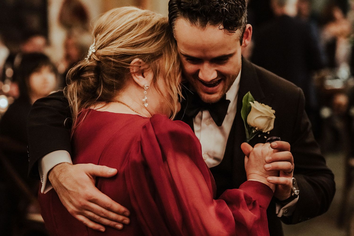 A couple shares an intimate dance moment together, with the person wearing a striking red dress.