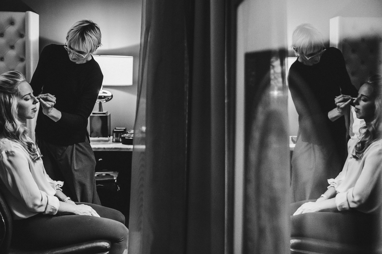 Black and white reflection of wedding preparations in a mirror.