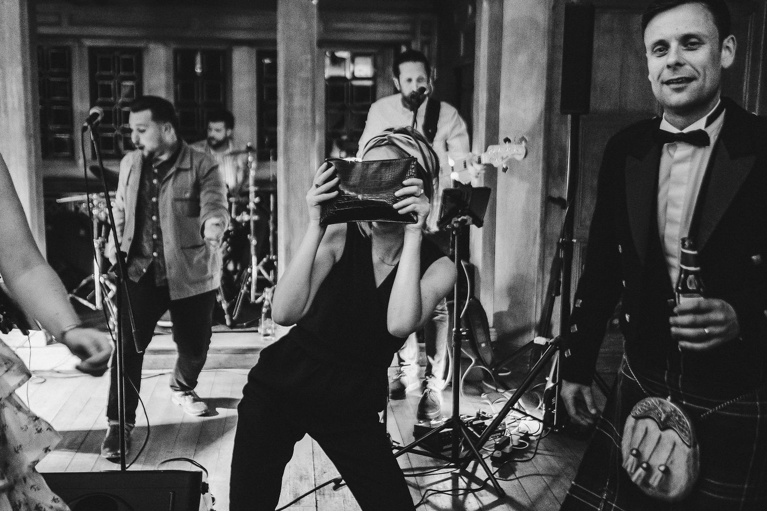 Live band performs at wedding reception while guests dance in the background.