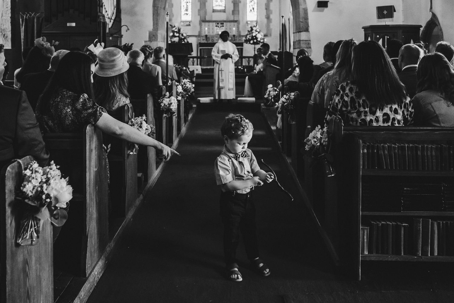 Black and white photo of a church ceremony with floral decorations.