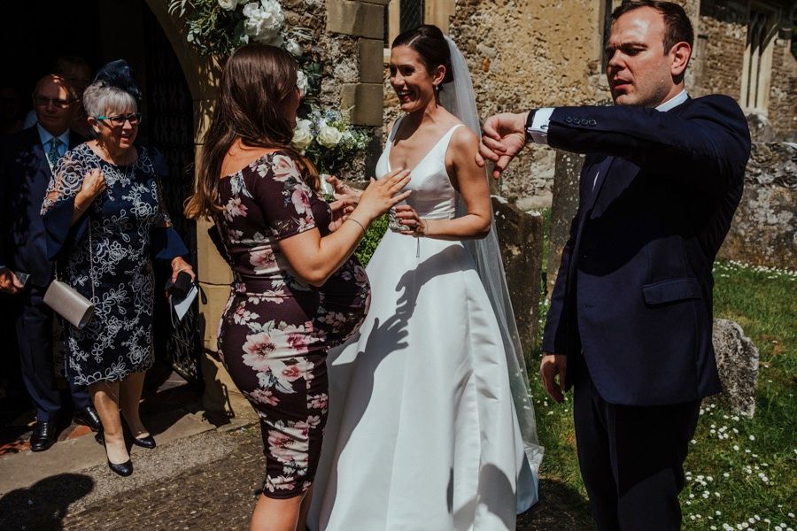 Wedding party mingling outdoors on stone patio during daytime celebration.