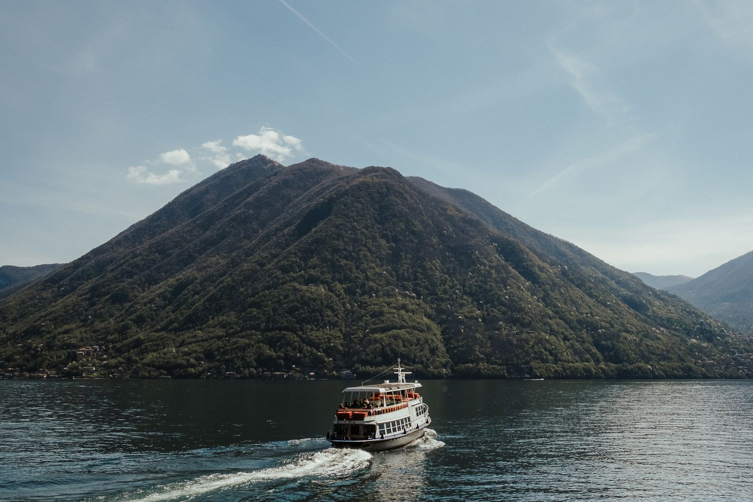 Tourist boat cruising on a pristine mountain lake surrounded by lush peaks.