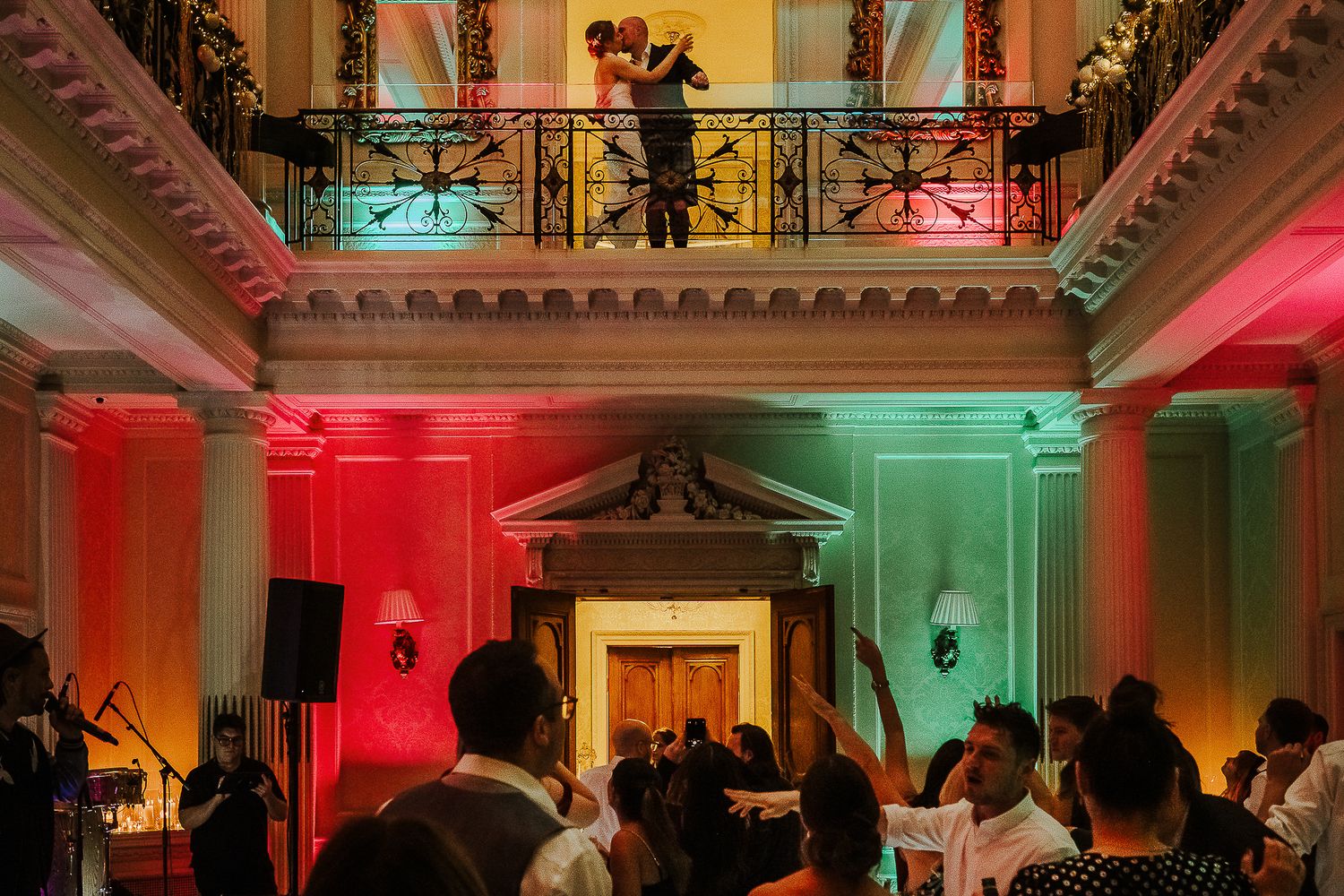 Wedding reception venue illuminated with dramatic red and green lighting creating an elegant atmosphere.