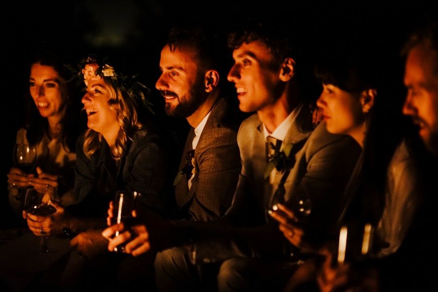Wedding guests illuminated by candlelight during evening celebration.