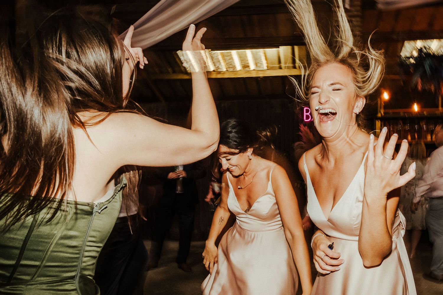 Wedding guests dancing enthusiastically at a reception with joyful expressions.