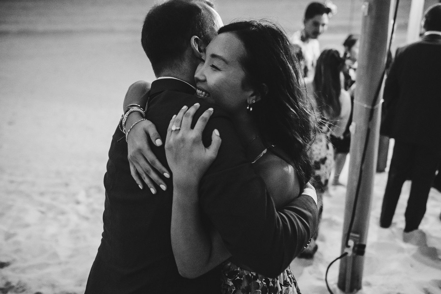 Black and white candid photo of emotional dance moment at beach wedding reception.