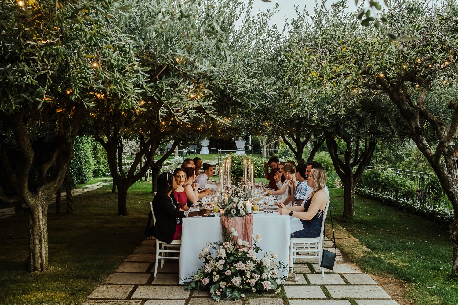Wedding reception setup in an olive grove with long tables and floral arrangements.