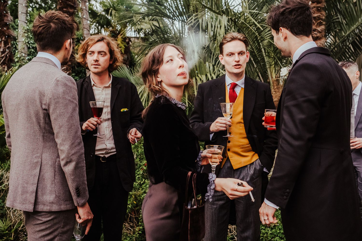 Wedding guests enjoying cocktails and conversation in a garden setting.