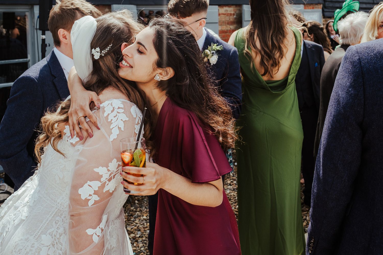 Friends embrace and celebrate during a wedding reception wearing elegant dresses.