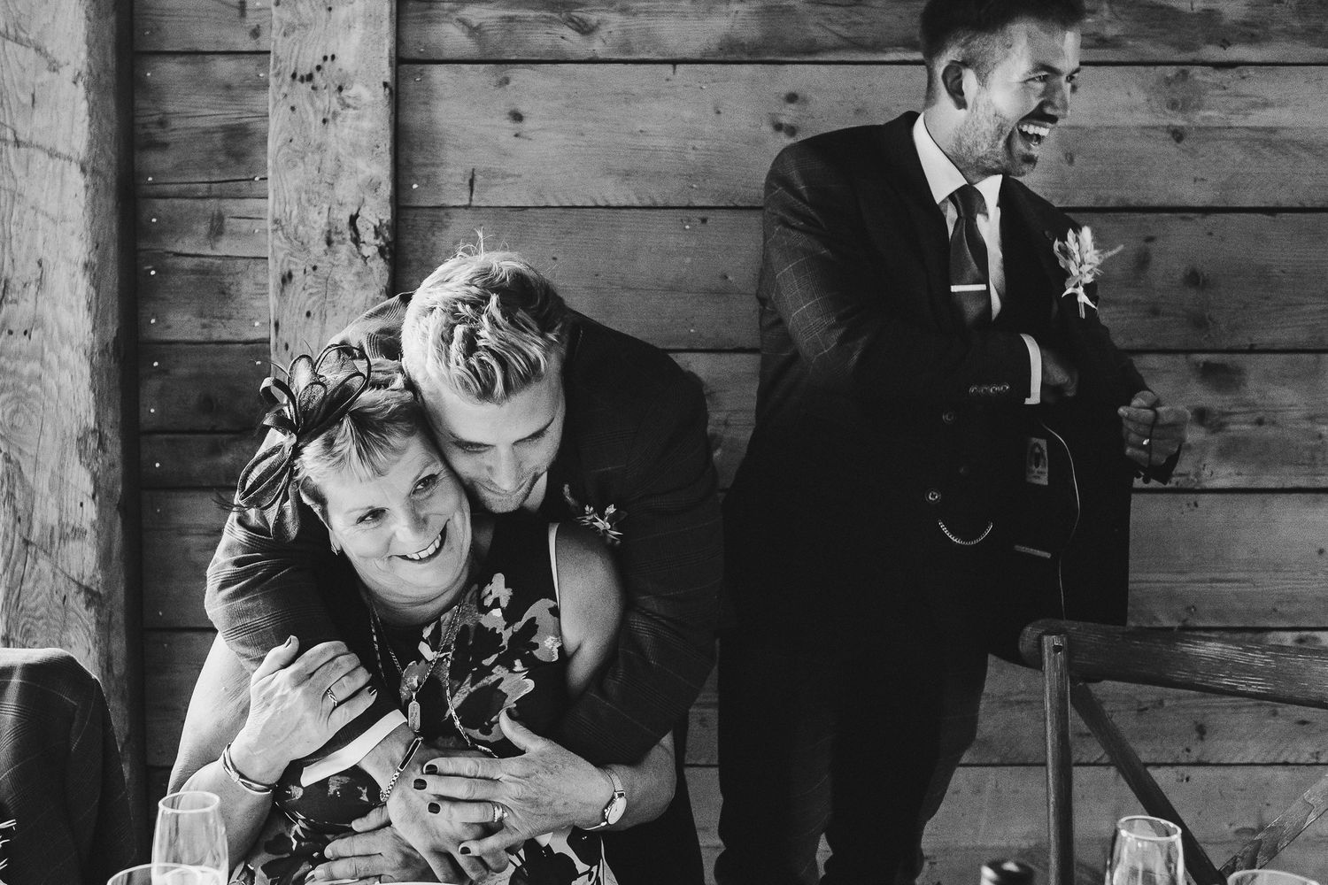 A rustic wooden barn wall serves as backdrop for an intimate wedding moment.