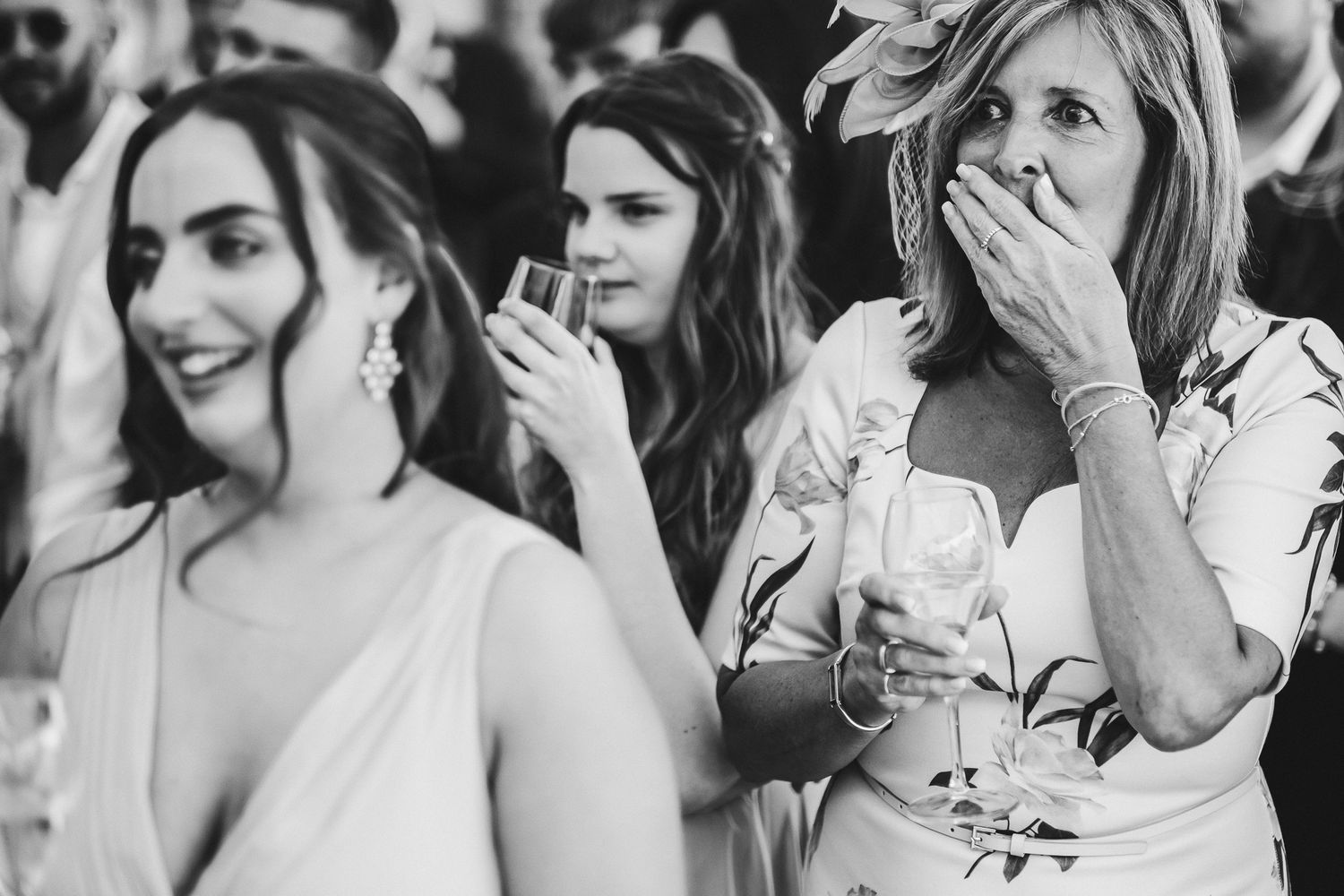 Black and white photo of wedding guests reacting with joy and laughter at an outdoor celebration.