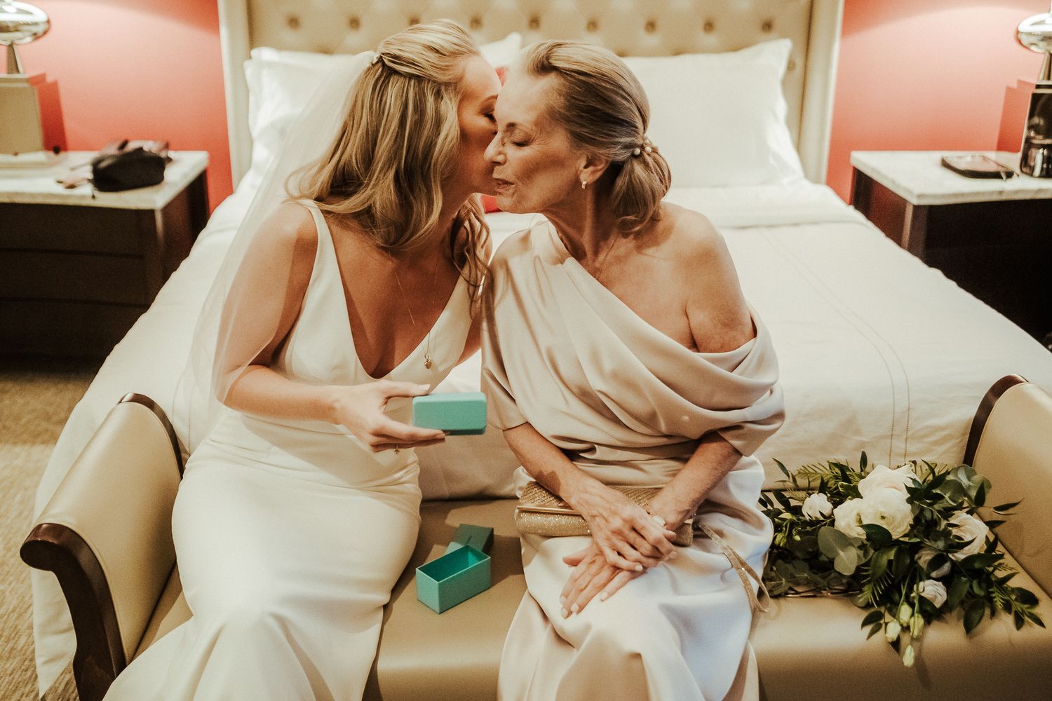 Two wedding attendees share an intimate moment while seated on an elegant cream-colored sofa.