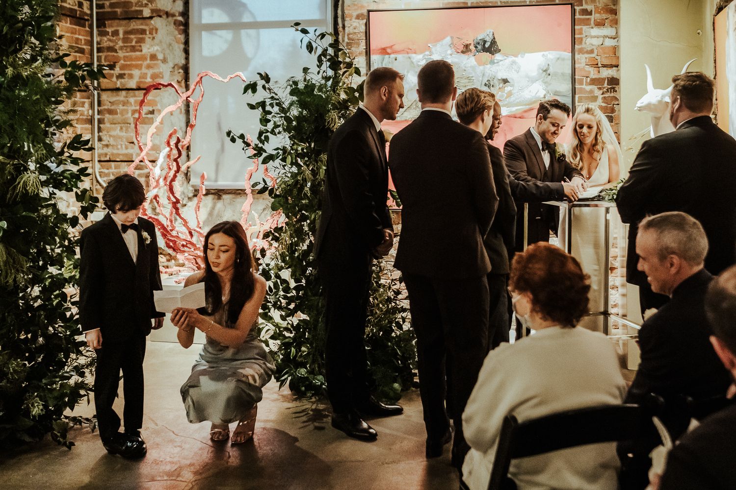 Evening wedding reception with guests mingling in industrial venue with brick walls.