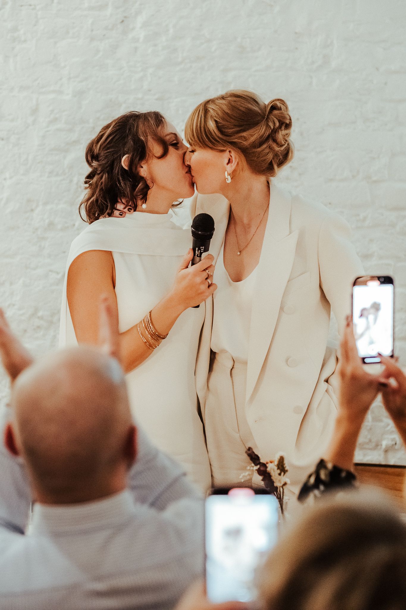 Intimate wedding moment captured with guests taking photos in the background.