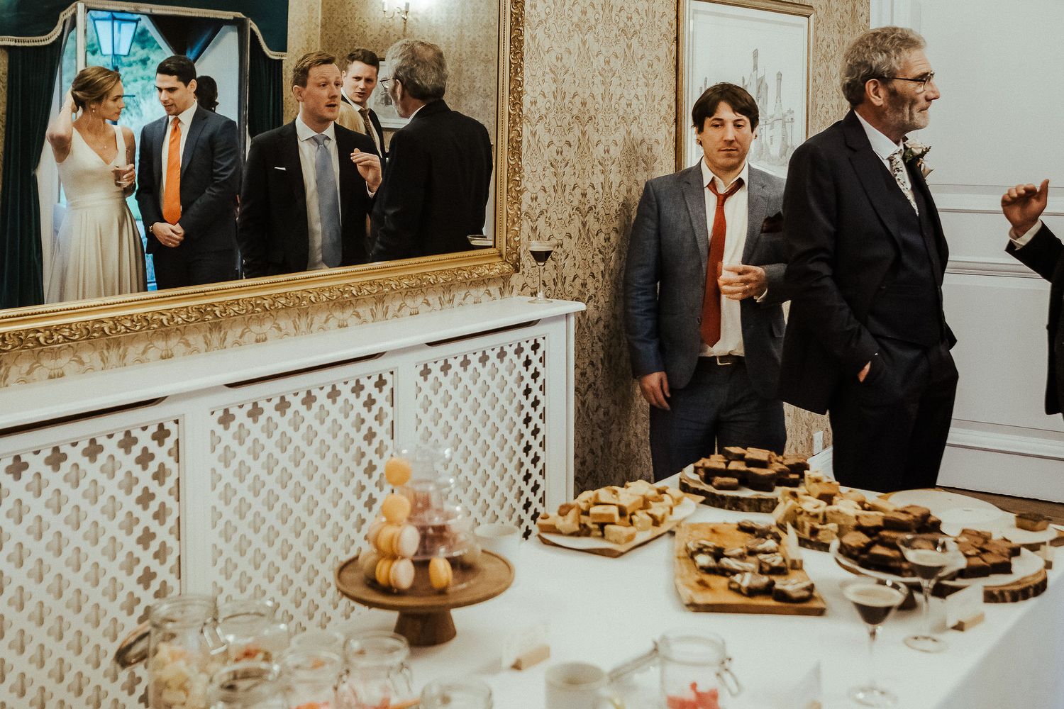 Guests enjoying appetizers and drinks at an elegant wedding reception with ornate decor.