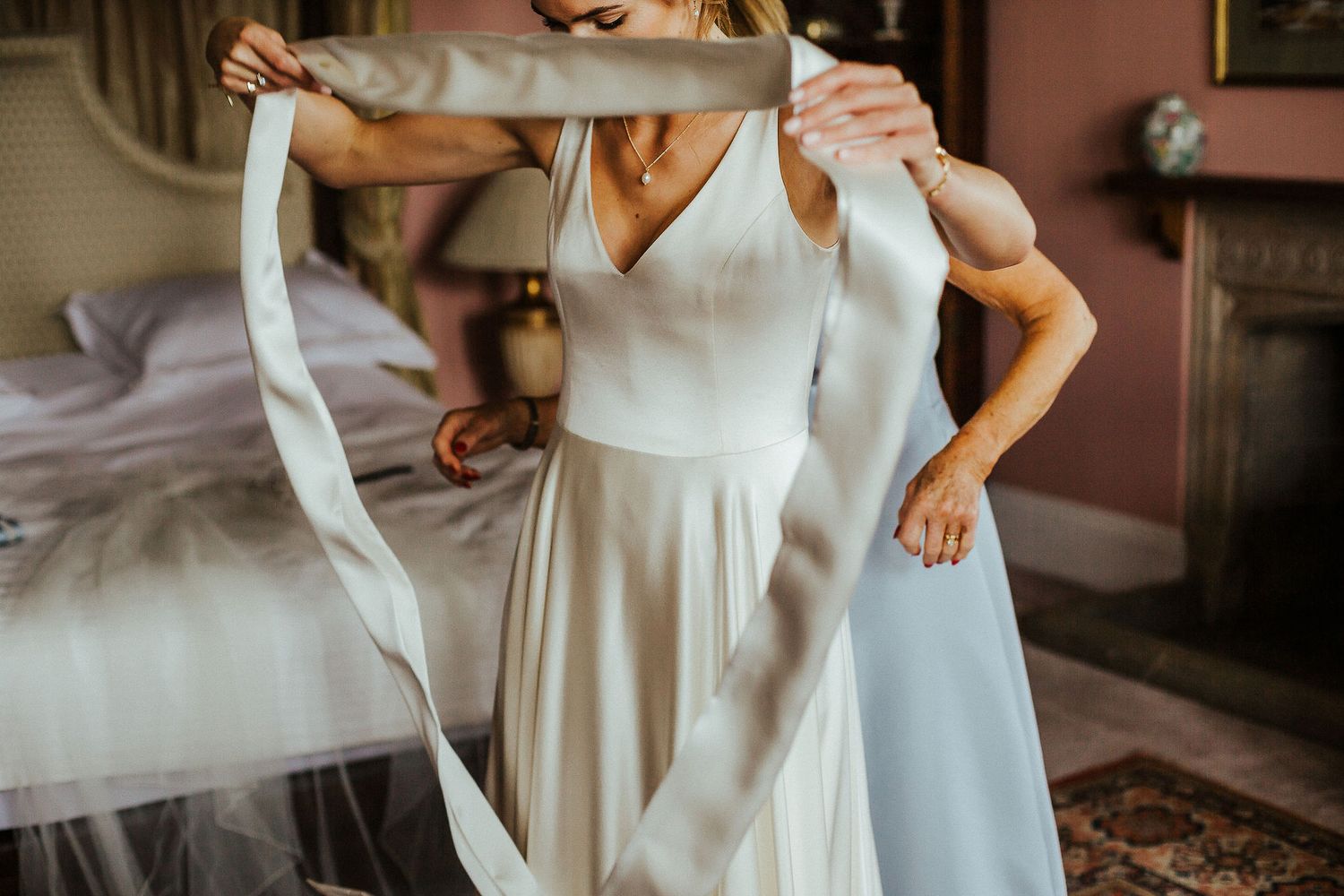 Detail shot of white wedding dress fabric being adjusted in a vintage room.