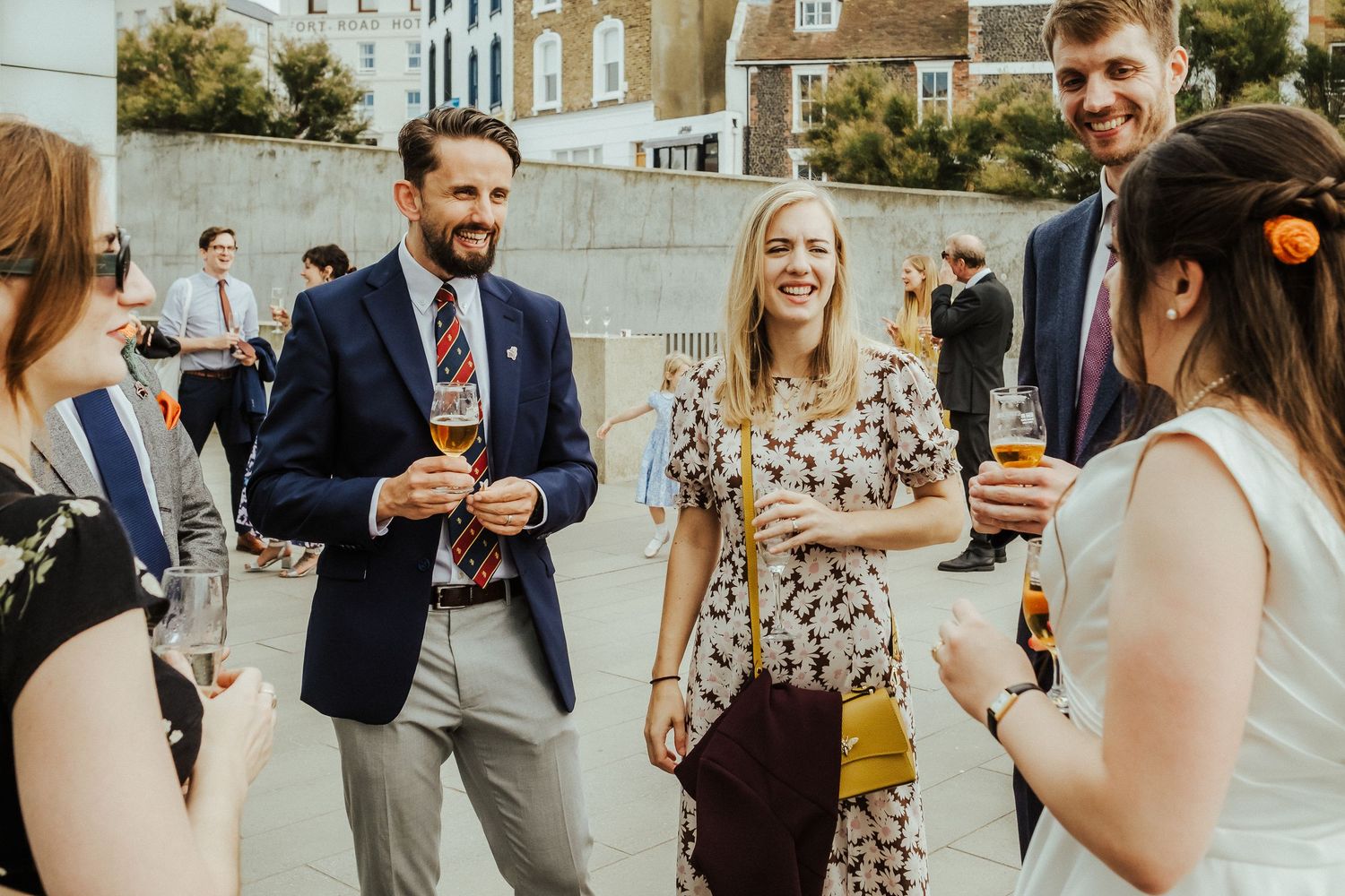 Wedding guests enjoying drinks and conversation in warm afternoon light.