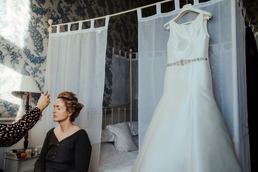 Multiple shots of a wedding dress being fitted and adjusted in a brightly lit dressing room.