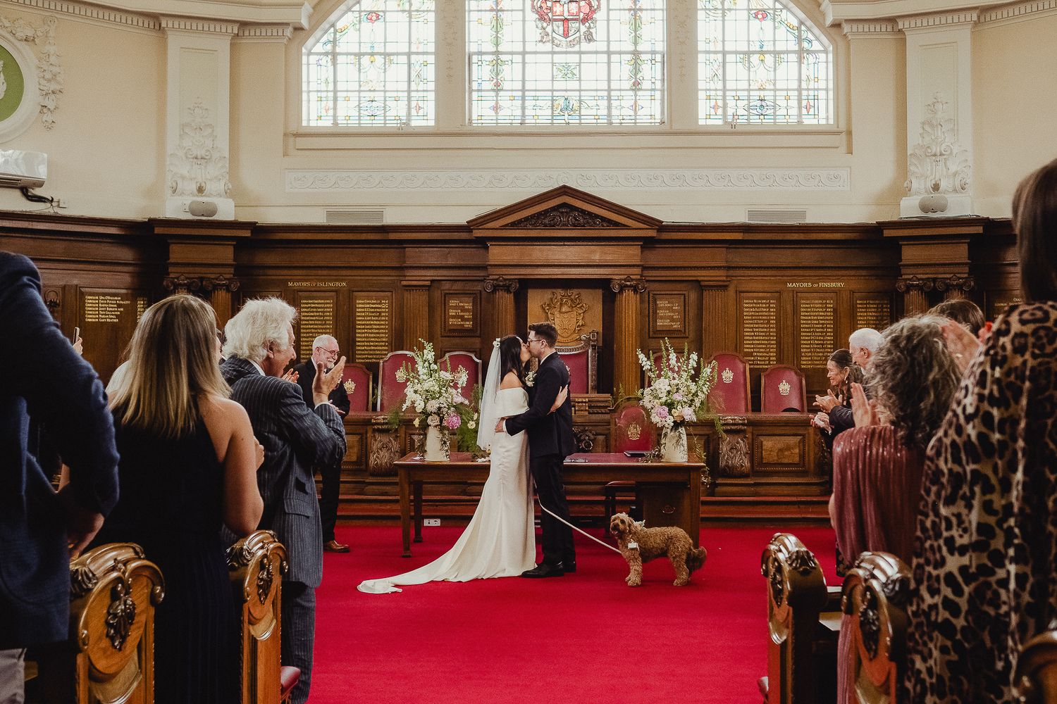 A beautiful church wedding ceremony with guests watching as a couple stands before an ornate altar on a red carpet.