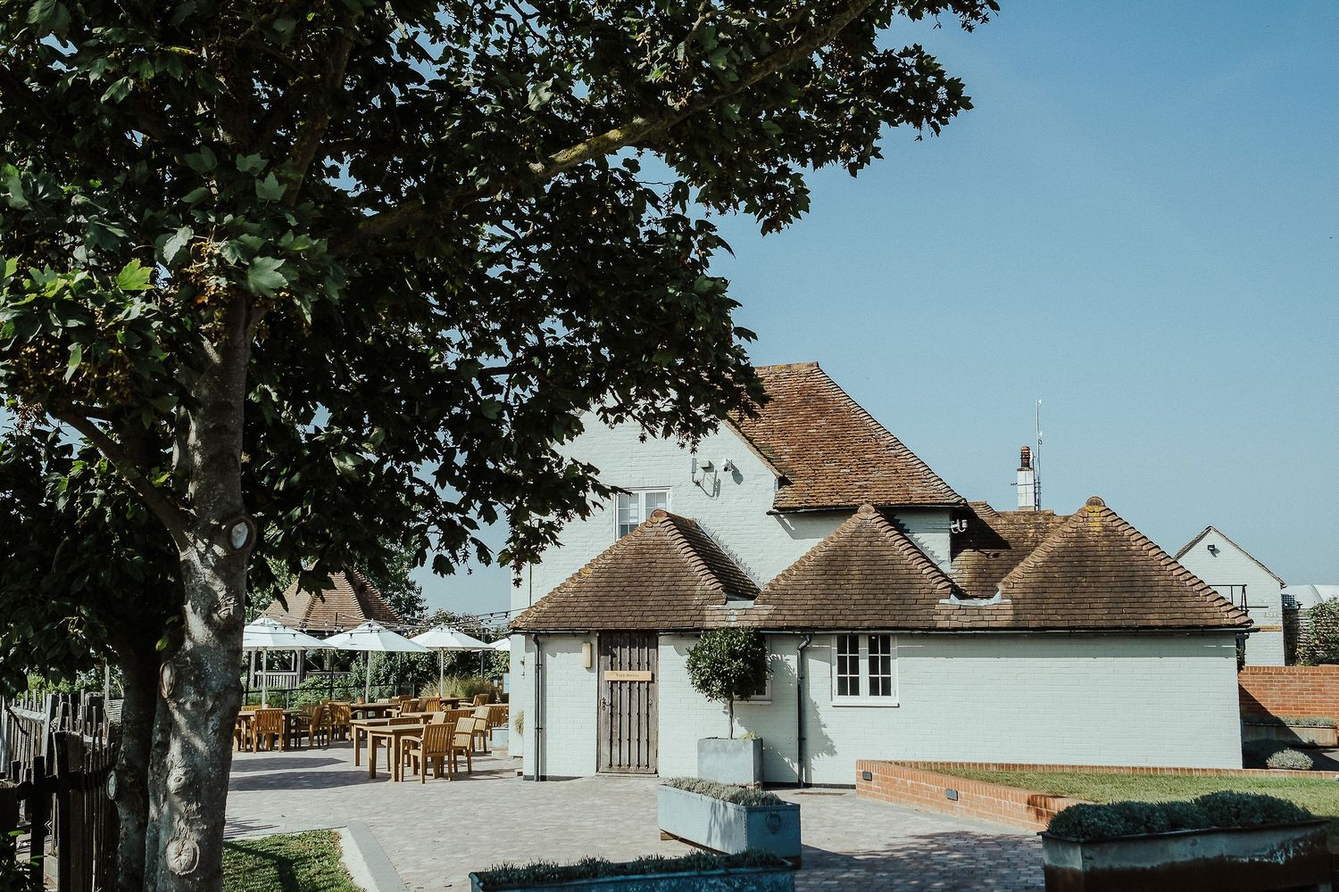 A charming white thatched-roof venue with outdoor seating area under blue summer skies.