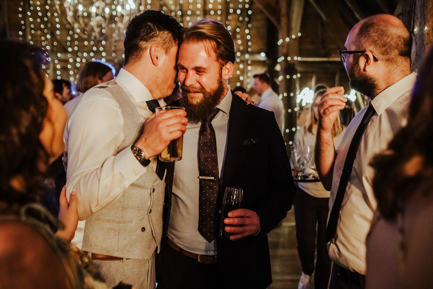Guests sharing drinks and laughs during a dimly lit wedding reception.