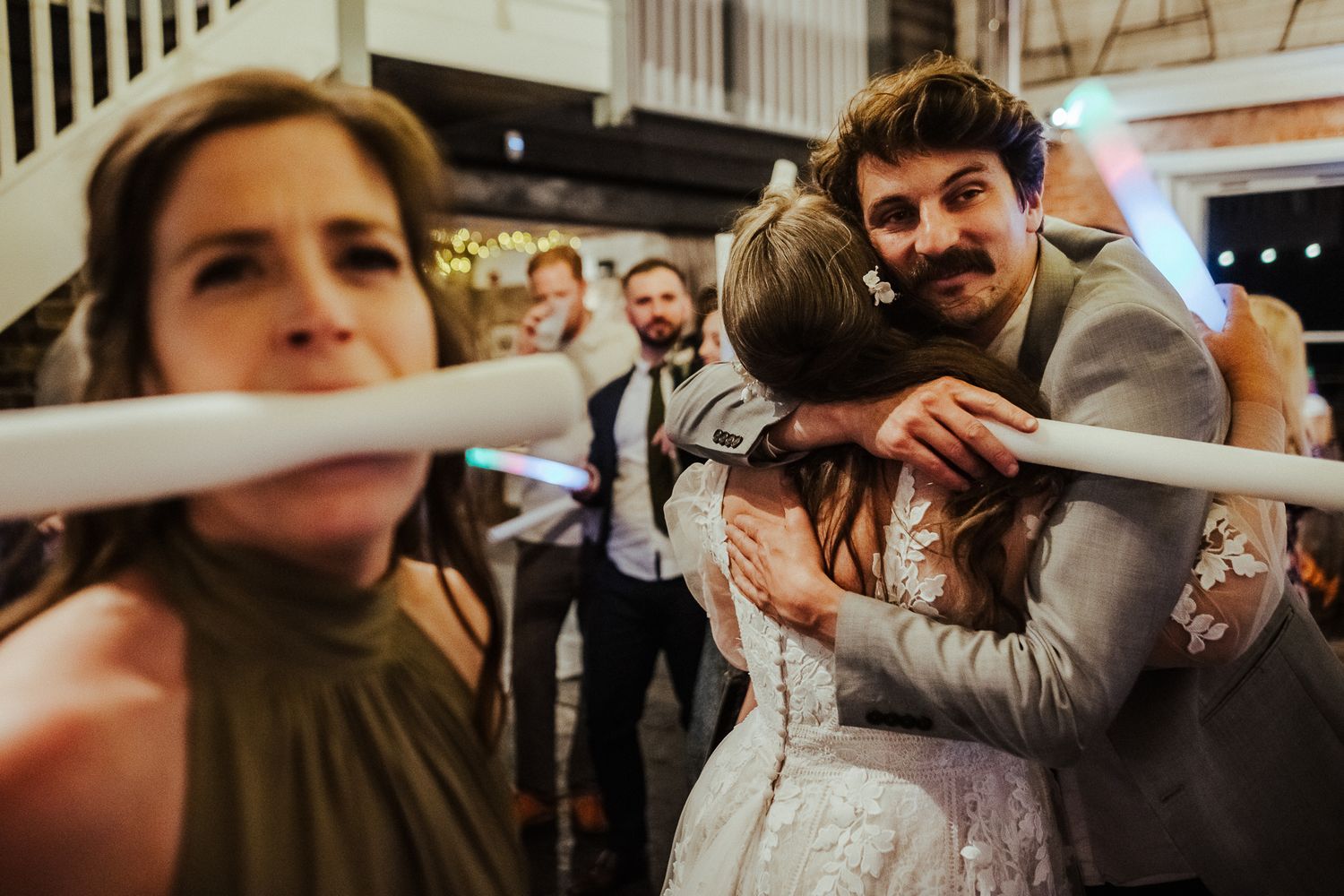 Fun candid moment of wedding guests playing limbo at reception.
