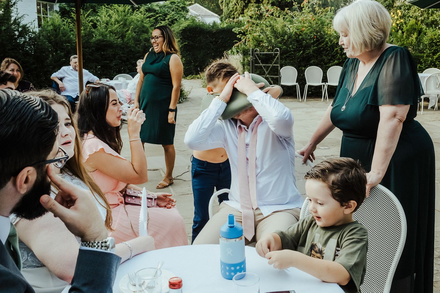 Wedding guests enjoy outdoor games and refreshments at a casual garden reception.
