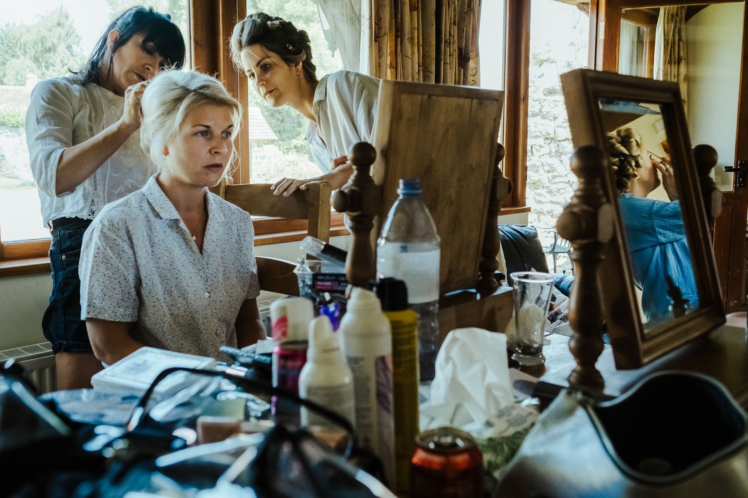 Behind the scenes of bridal preparations with stylists working in sunlit room.