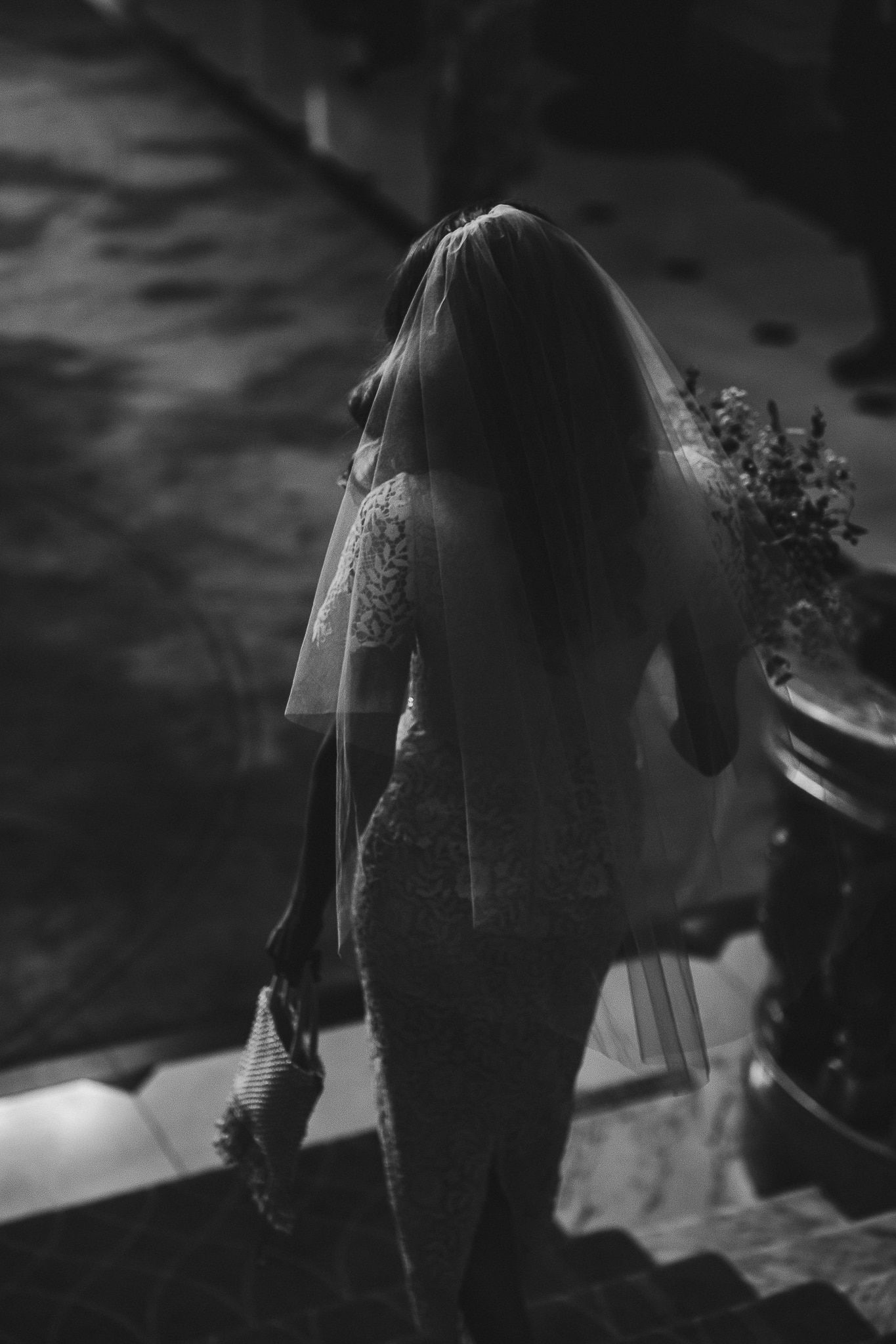 Silhouette of bride in lace dress descending stairs in dramatic black and white.