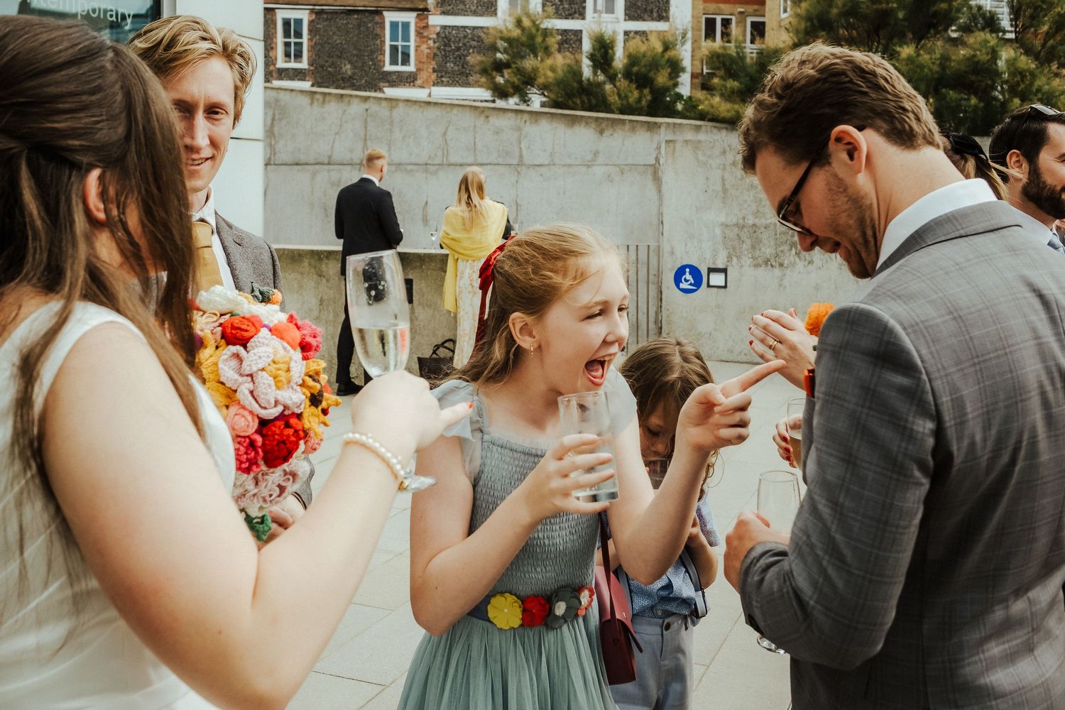 Wedding guests enjoying drinks and laughter during an outdoor reception celebration.