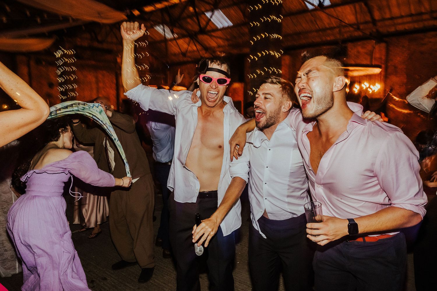 Energetic wedding reception dancing with guests in formal attire.