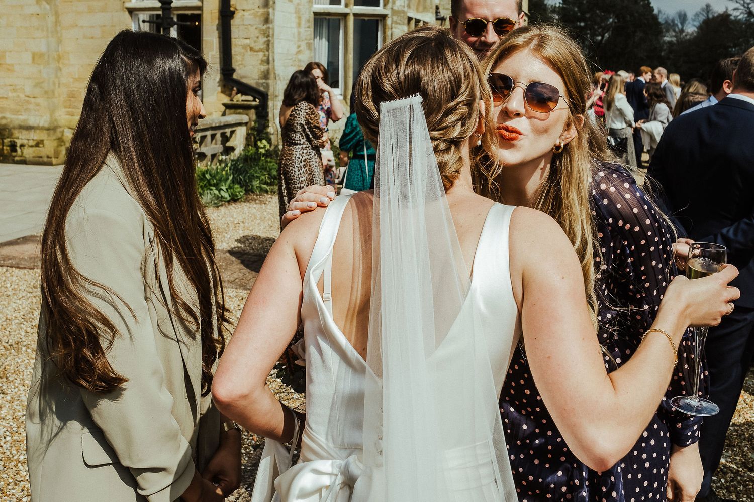 Guests enjoying outdoor wedding reception with bride in sunglasses.
