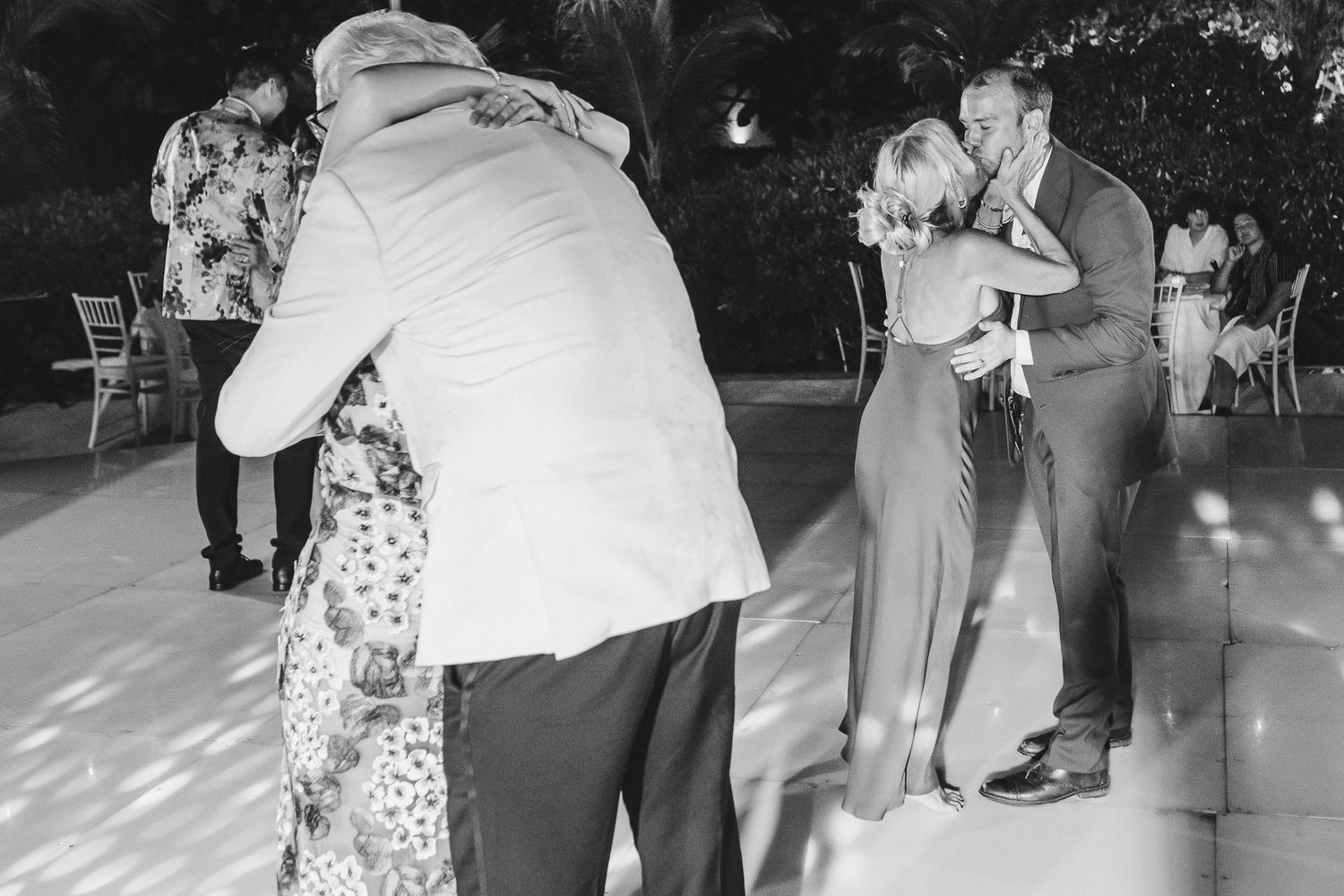Wedding guests dancing together on an illuminated dance floor.