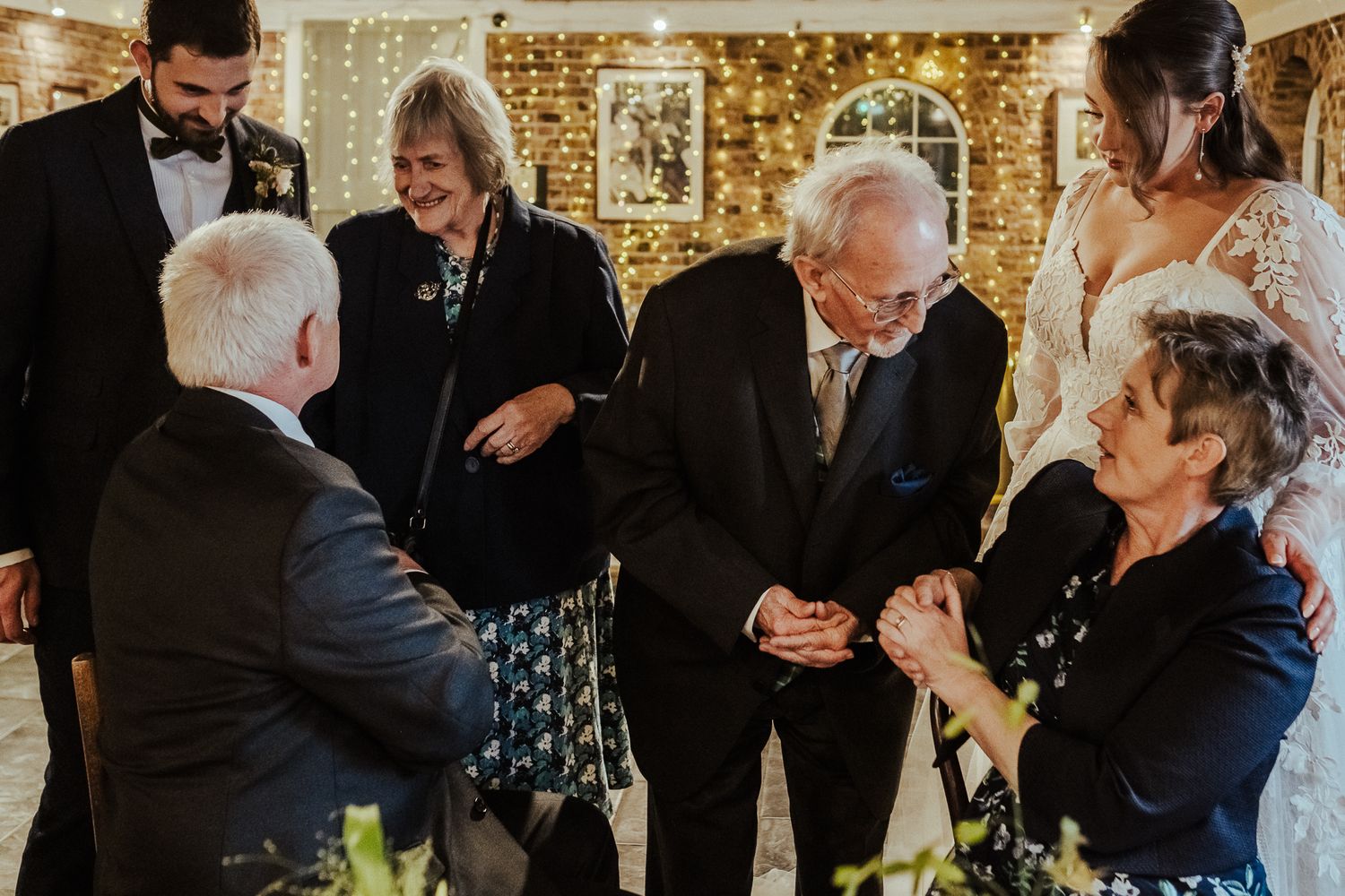 Wedding guests sharing emotional interactions during intimate reception moment.