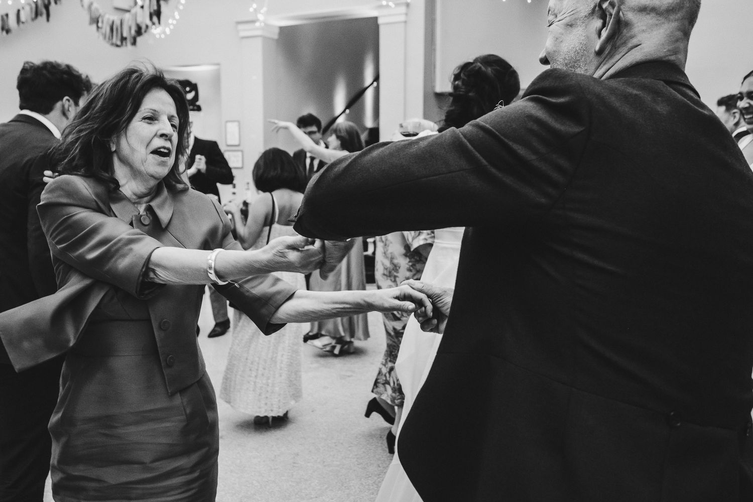 Black and white photo of guests dancing energetically at wedding reception.