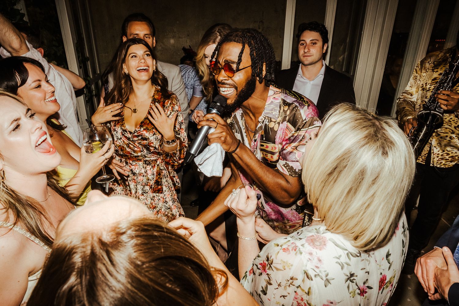 Wedding guests dancing and singing along with a musician at a vibrant reception party.