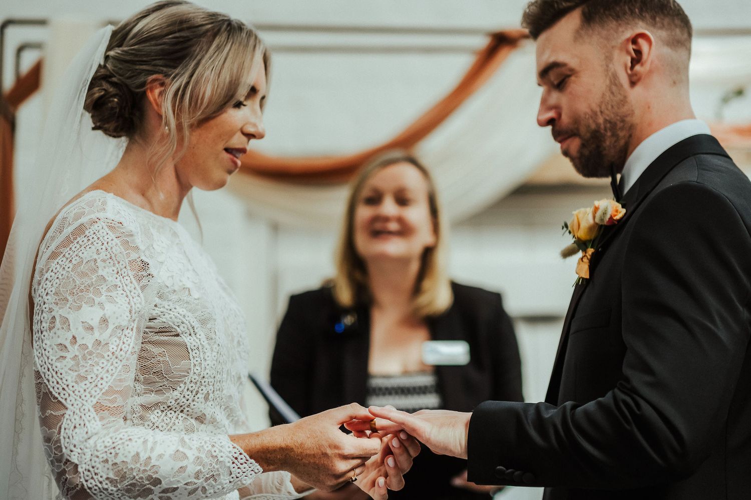 Intimate wedding ceremony exchange of rings in light-filled room.